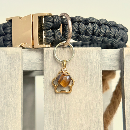 Crystal for dogs pet collar charm featuring a 10mm tigers eye heart shaped bead and a brass gold coloured paw print tag. Close up picture.