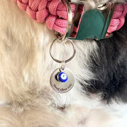 Silver plated brass and stainless steel 15mm dog collar charm with ID tag. Personalised custom identification tag with a small, blue Turkish Evil Eye charm, on a 15mm silver split ring. Engraved with the words ‘Good vibes only’ on the front. Pictured close up.