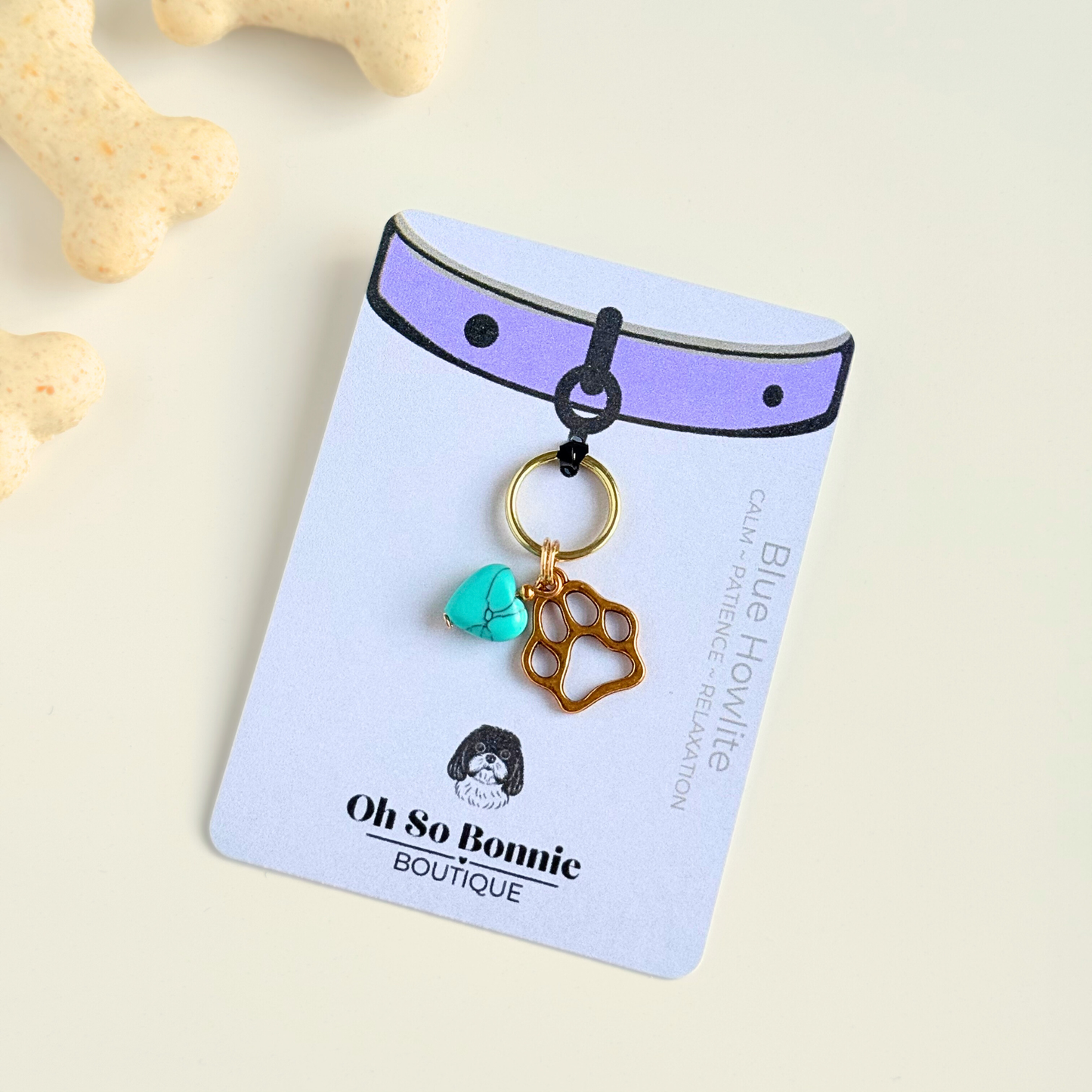Crystal for dogs pet collar charm featuring a 10mm turquoise blue howlite heart shaped bead and a brass gold coloured paw print tag. On the display card.