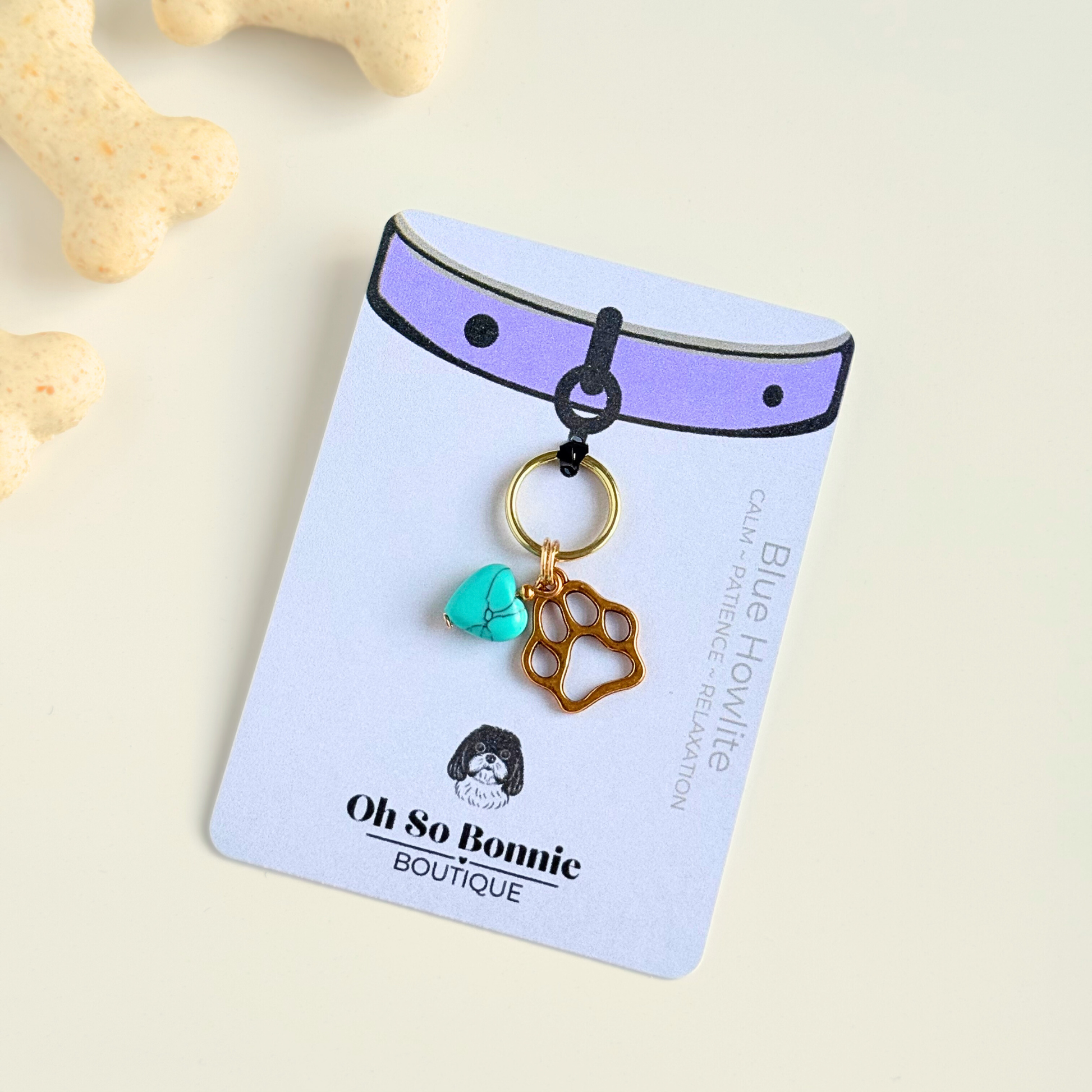 Crystal for dogs pet collar charm featuring a 10mm turquoise blue howlite heart shaped bead and a brass gold coloured paw print tag. On the display card.
