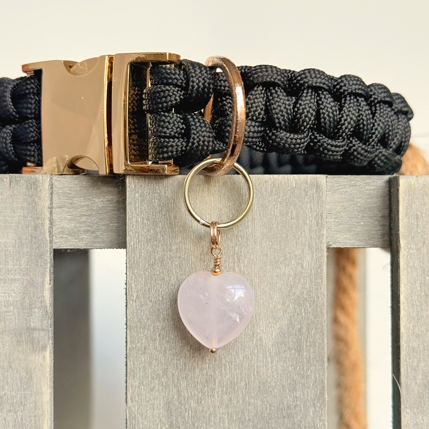 Handmade dog collar charm featuring a 15mm pink rose quartz natural gemstone crystal bead. Hung on a gold plated brass split ring that attaches onto your pet collar. Rose quartz can help pets with love, comfort and calming. Pictured attached to a black paracord dog collar.