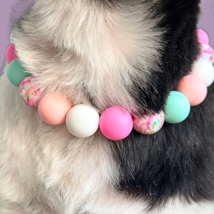 Silicone beaded dog necklace made with 15mm round beads in pink, green, white and a floral flowers print. On a strong, elastic stretch cord. Close-up picture of Bonnie wearing the beads.￼