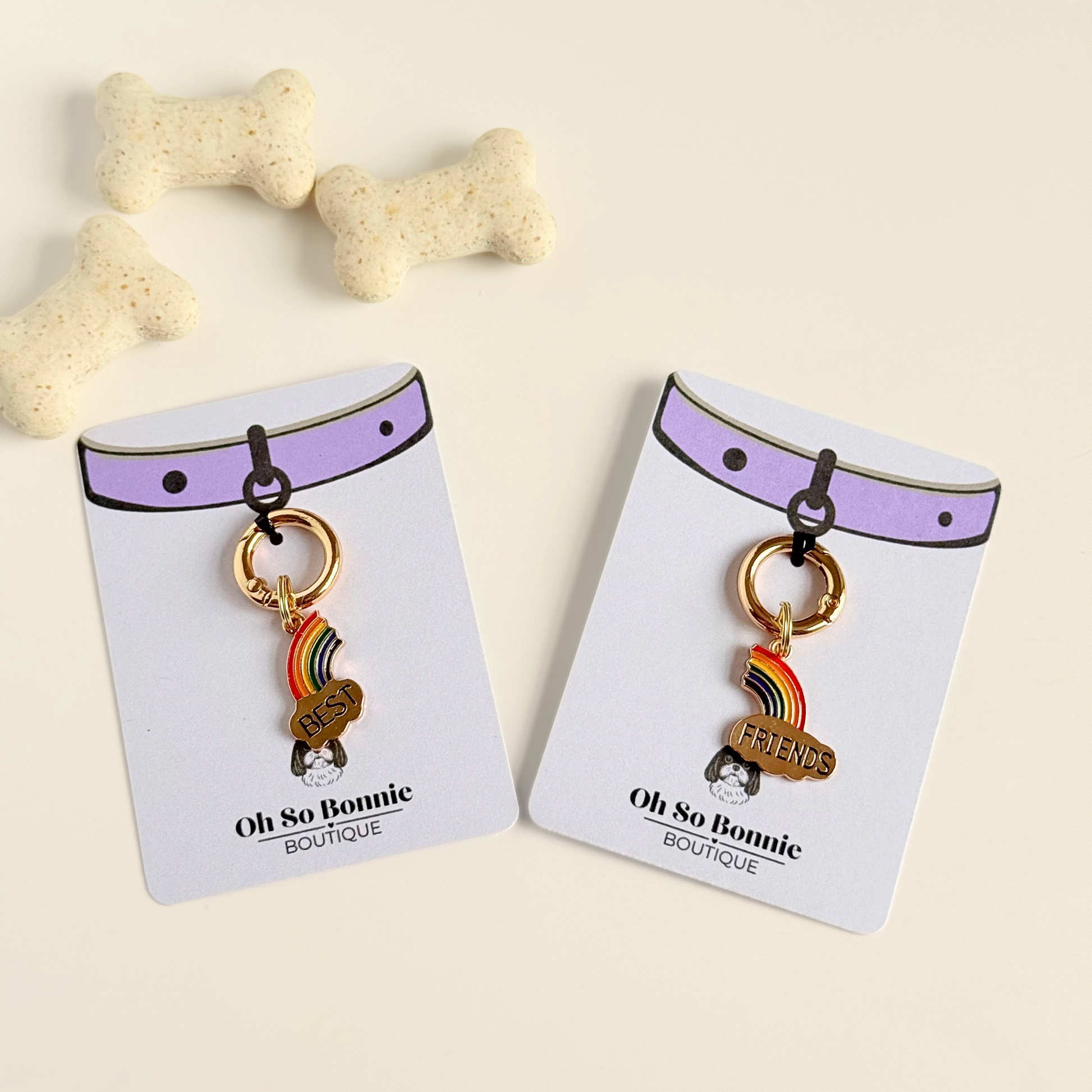 Set of two ‘best friends’ matching dog collar charm and keyring. With enamel rainbow gold plated charms, on secure carabiner style O-rings, for easy use. Pictured on the display cards, next to some dog biscuits.