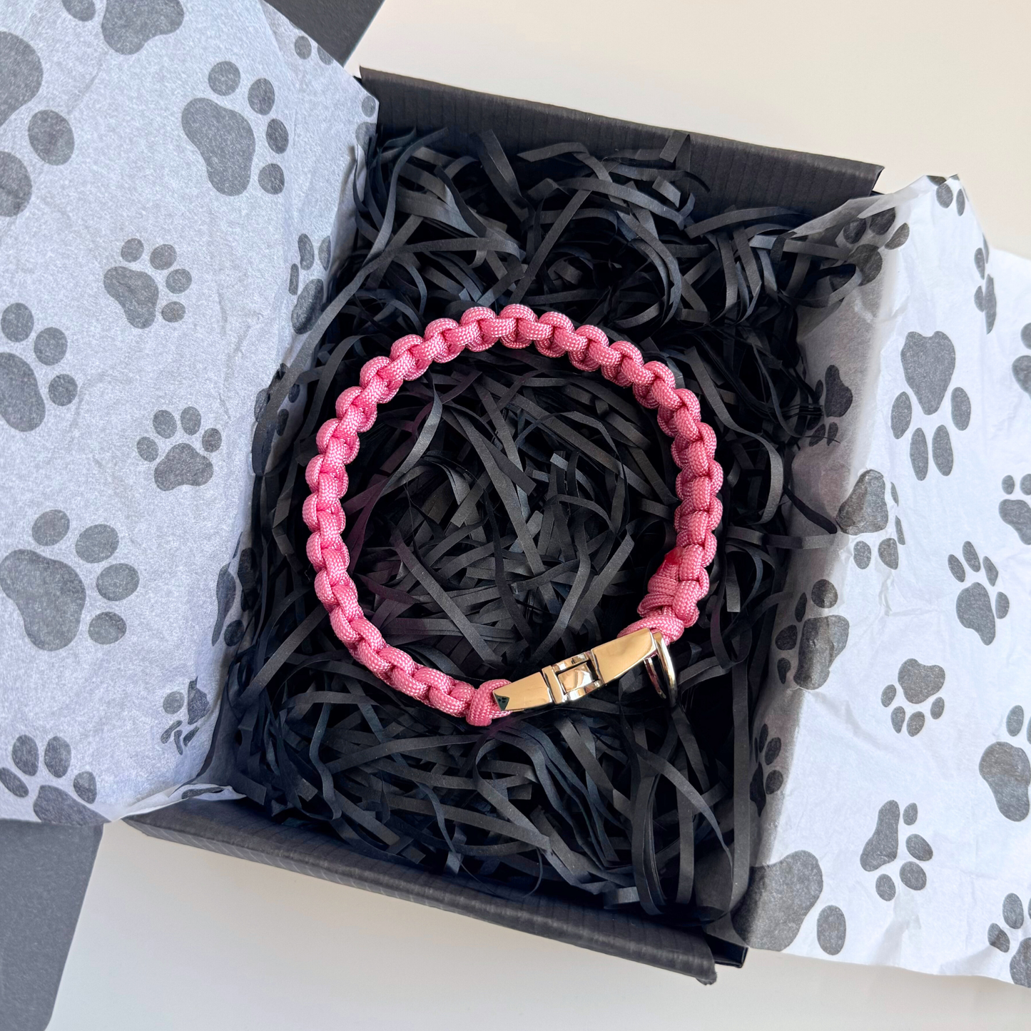 ‘Lavender pink’ handmade paracord dog collar with silver coloured buckle clasp. Custom made to your required size. Braided macrame style pet neckwear. Pictured in front of the gift box. Pictured in gift box.