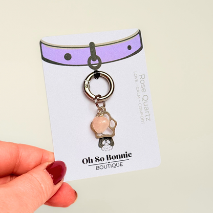 Crystal for dogs pet collar charm featuring a 10mm rose quartz heart shaped bead and a brass silver coloured paw print tag. A stone for love, calm and comfort. Pictured on the display card.