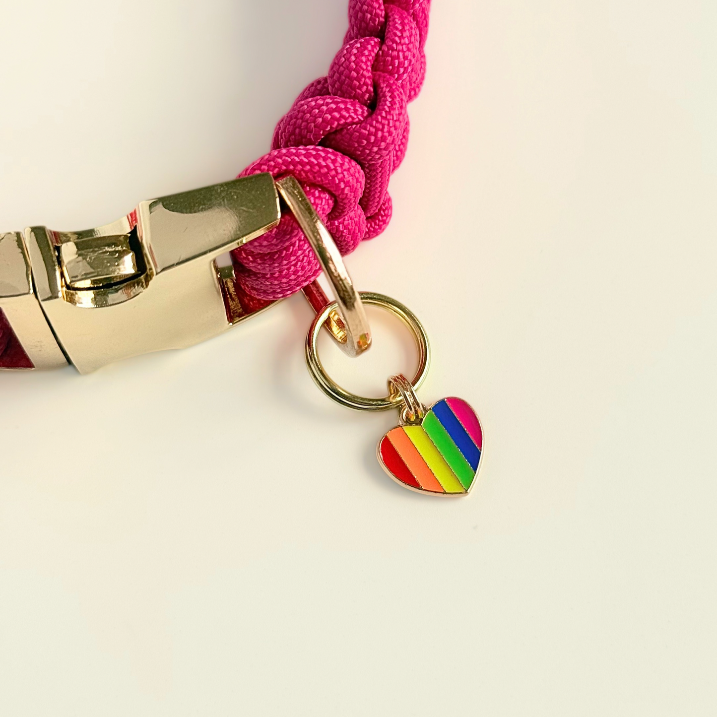 Rainbow striped heart shaped dog collar charm made with an enamel charm and a gold plated brass split ring. Pictured attached to  pink paracord dog collar.