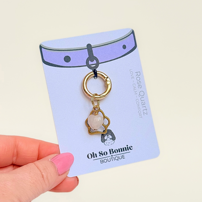 Crystal for dogs pet collar charm featuring a 10mm rose quartz heart shaped bead and a brass gold coloured paw print tag. A stone for love, calm and comfort. Pictured on the display card.