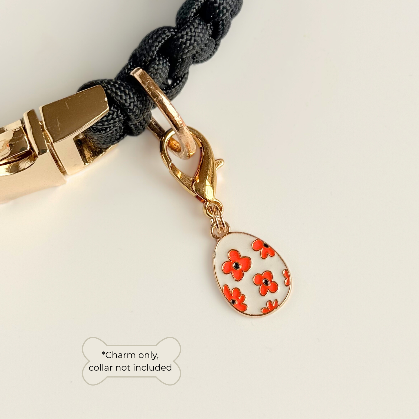 White with red flowers Easter egg enamel dog collar charm that easily attaches to collars and harnesses with a gold plated lobster clasp. Pictured attached to a black paracord dog collar.

￼