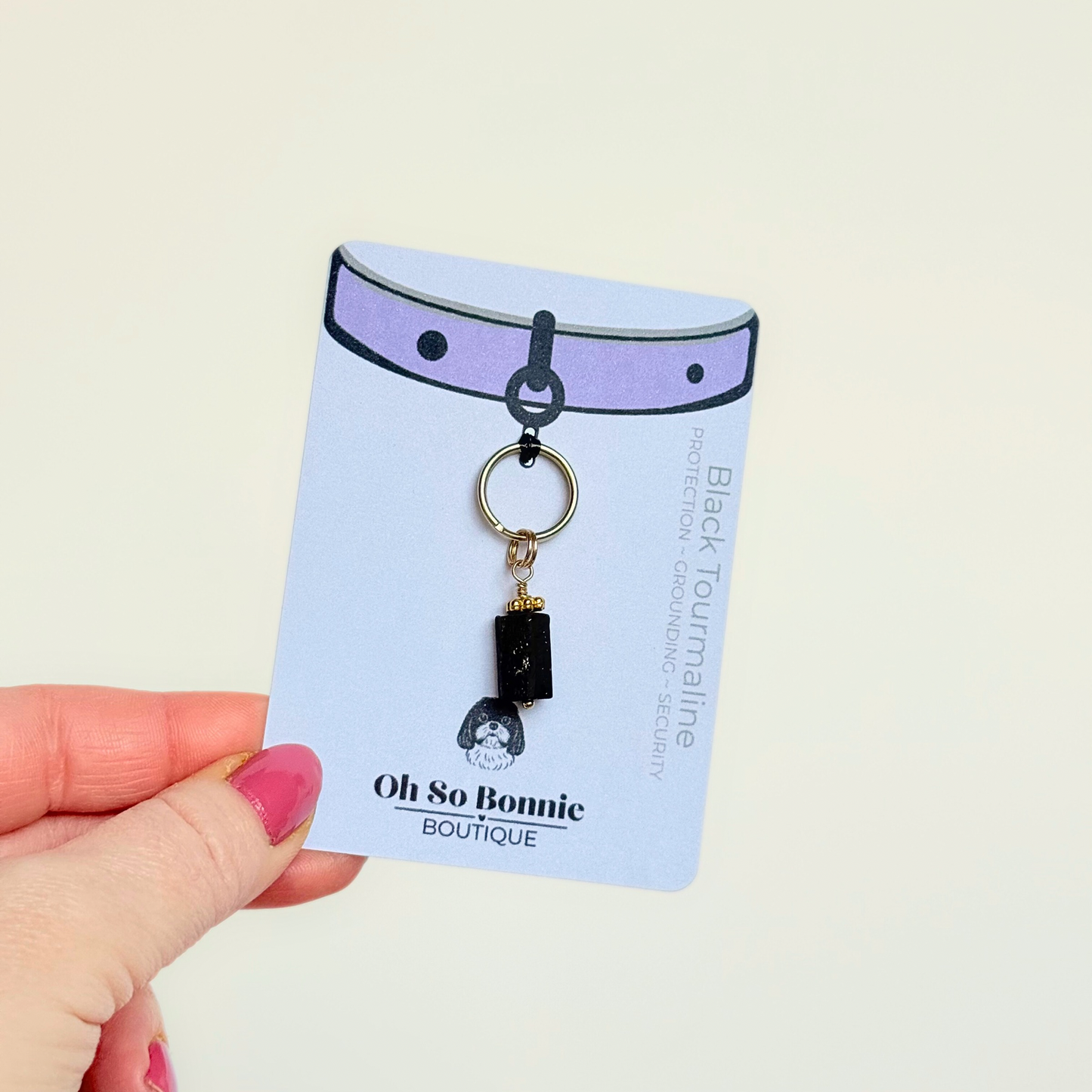 Crystal dog collar charm featuring a raw black tourmaline natural bead with gold plated accents. Featuring a brass split ring for easy attaching to your pet’s collar. Pictured on the display card.