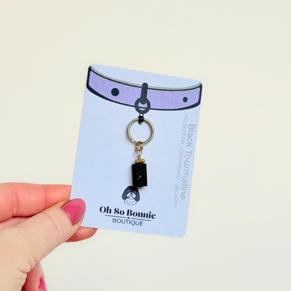 Crystal dog collar charm featuring a raw black tourmaline natural bead with gold plated accents. Featuring a brass split ring for easy attaching to your pet’s collar. Pictured on the display card.