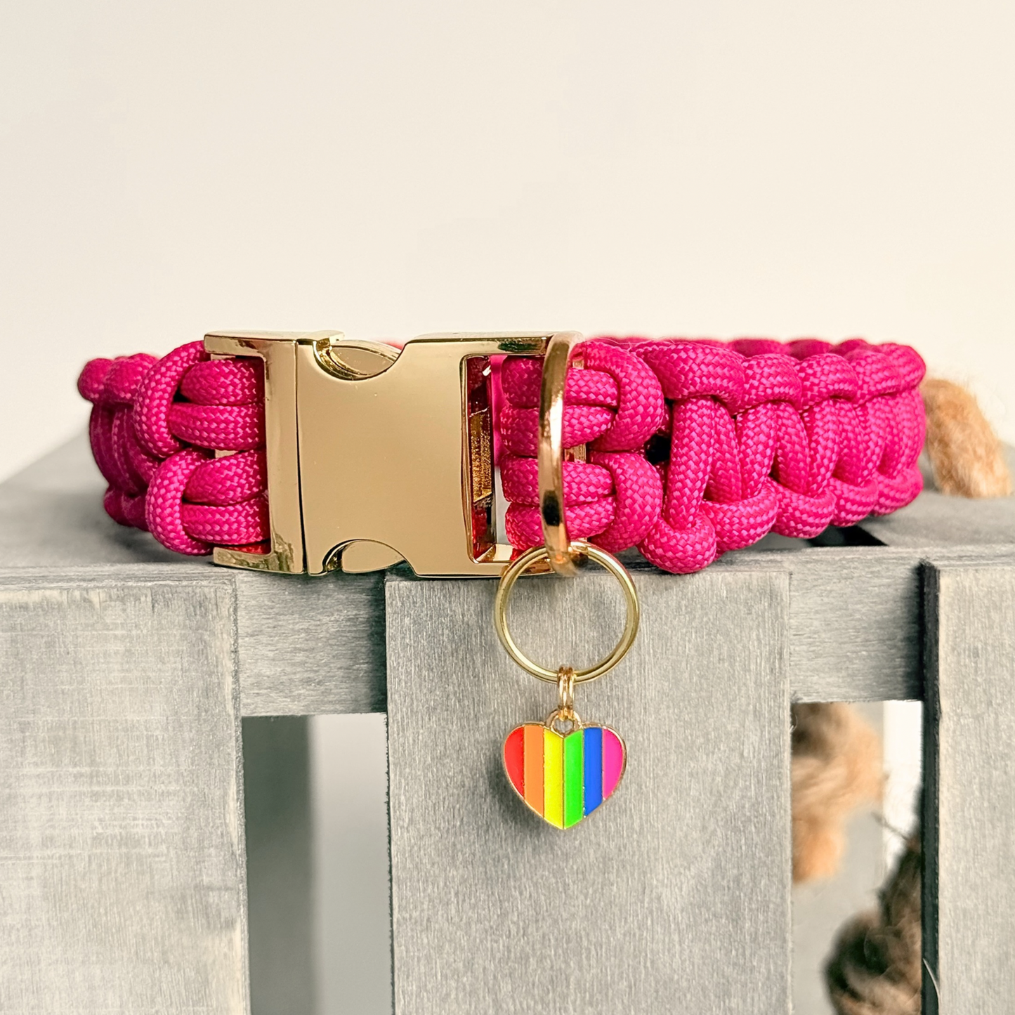 Rainbow striped heart shaped dog collar charm made with an enamel charm and a gold plated brass split ring. Pictured attached to a pink paracord dog collar.