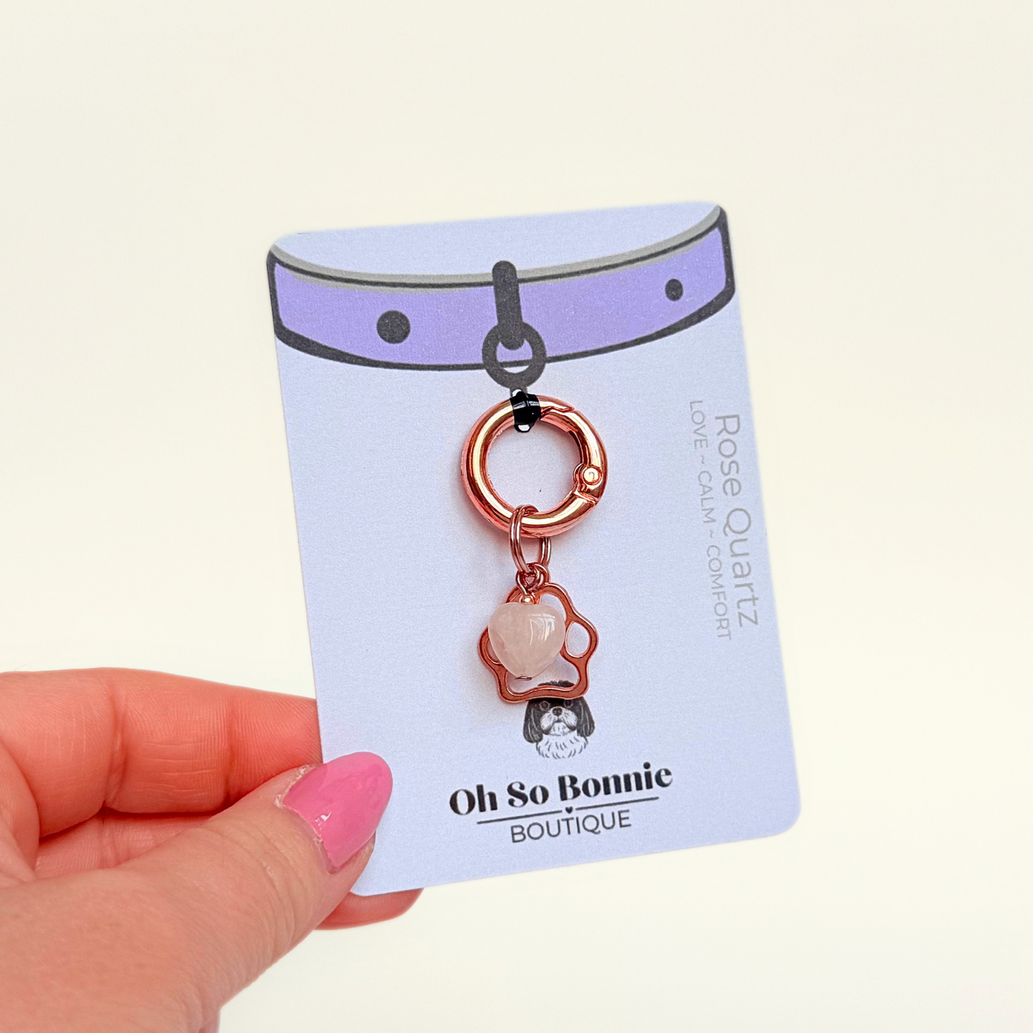 Crystal for dogs pet collar charm featuring a 10mm rose quartz heart shaped bead and a brass rose-gold coloured paw print tag. A stone for love, calm and comfort. Pictured on the display card.