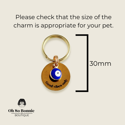 Gold plated brass and stainless steel 15mm dog collar charm with ID tag. Personalised custom identification tag with a small, blue Turkish Evil Eye charm, on a 15mm brass split ring. Engraved with the words ‘Good vibes only’ on the front. Pictured against a cream background showing the dimensions of the charm.