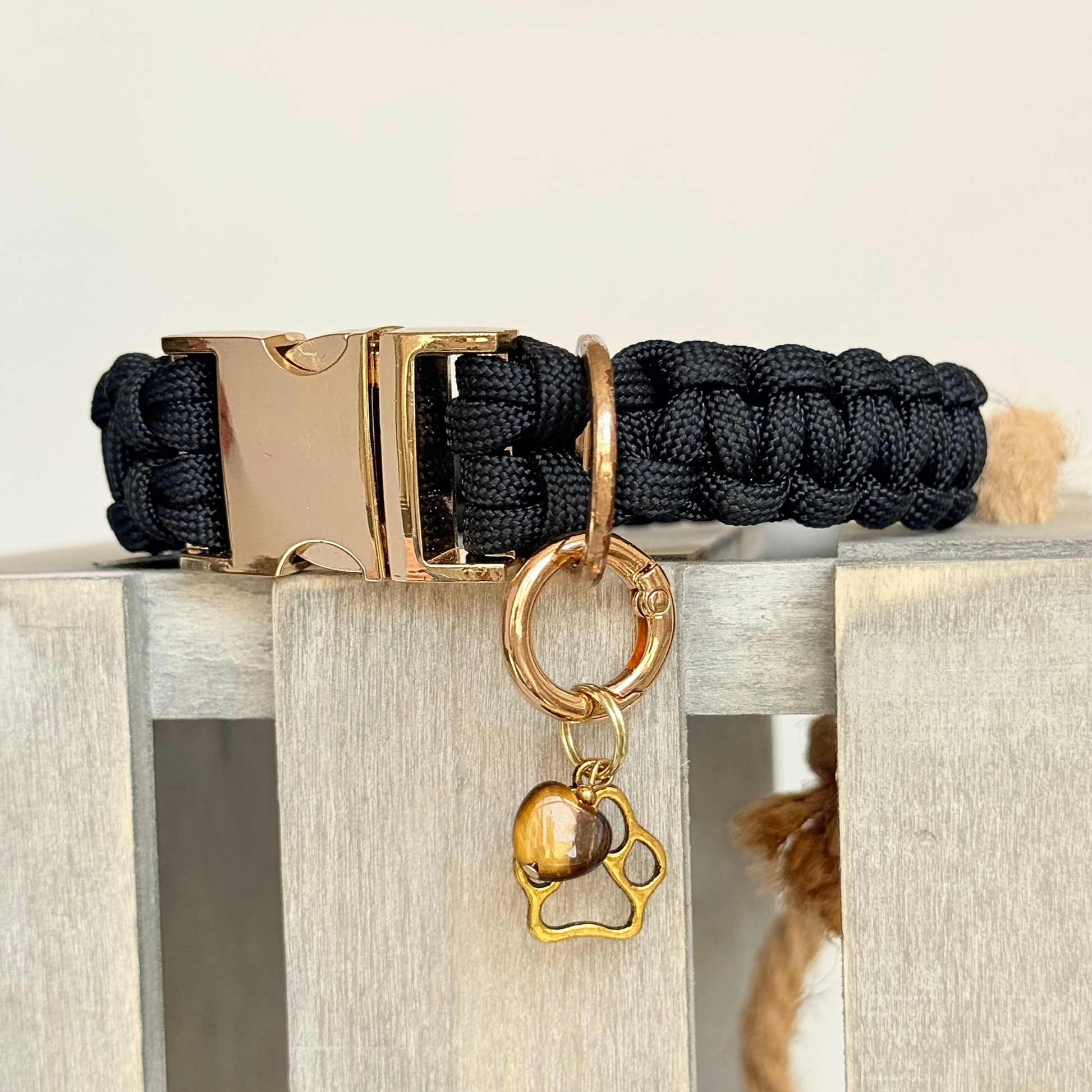 Crystal for dogs pet collar charm featuring a 10mm tigers eye heart shaped bead and a brass gold coloured paw print tag. Close up picture.