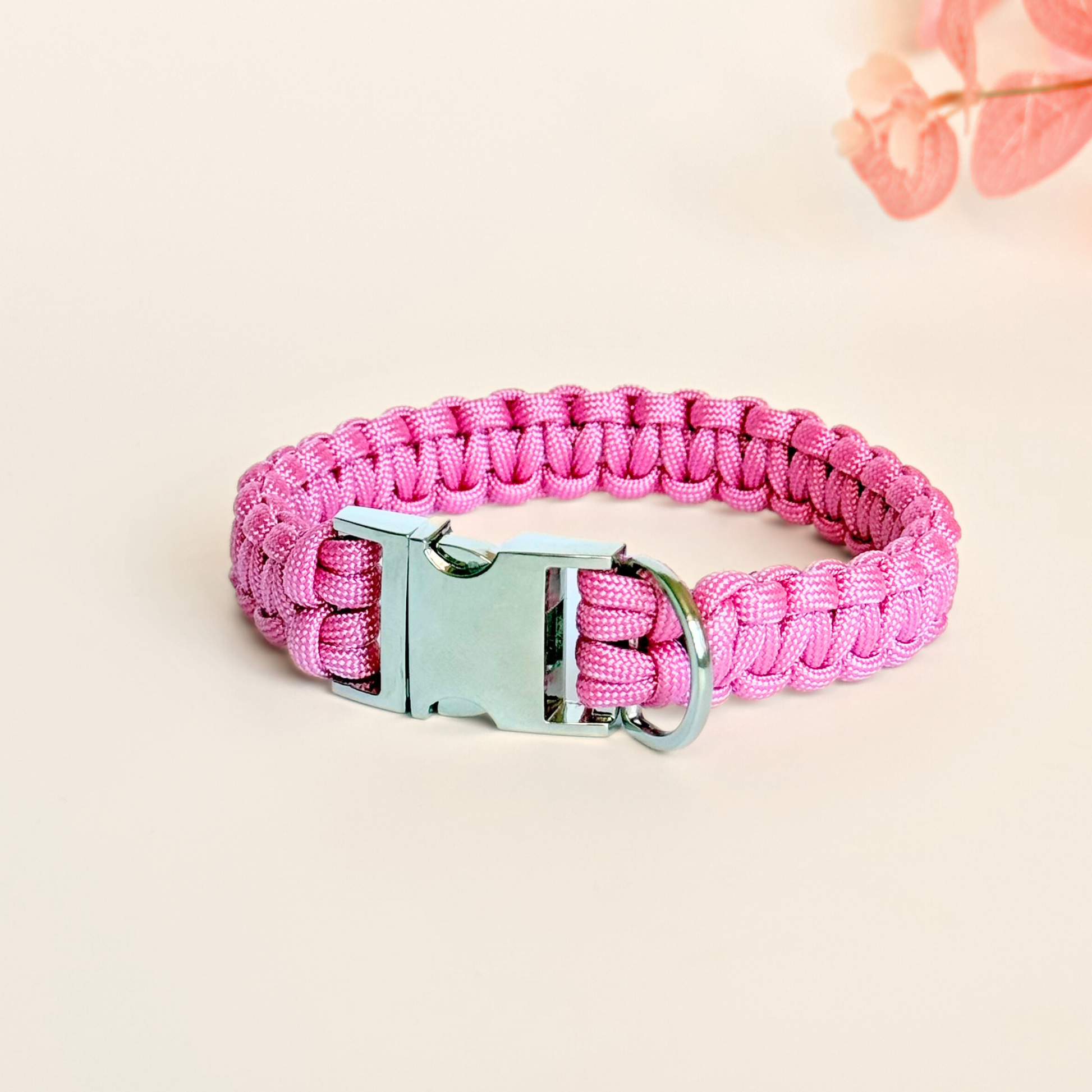 ‘Lavender pink’ handmade paracord dog collar with silver coloured buckle clasp. Custom made to your required size. Braided macrame style pet neckwear. Pictured against a cream background.