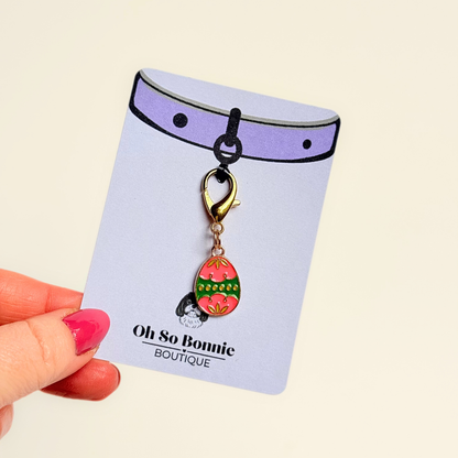 Colourful pink and green patterned Easter egg enamel dog collar charm that easily attaches to collars and harnesses with a gold plated lobster clasp. Pictured attached to the display card.￼