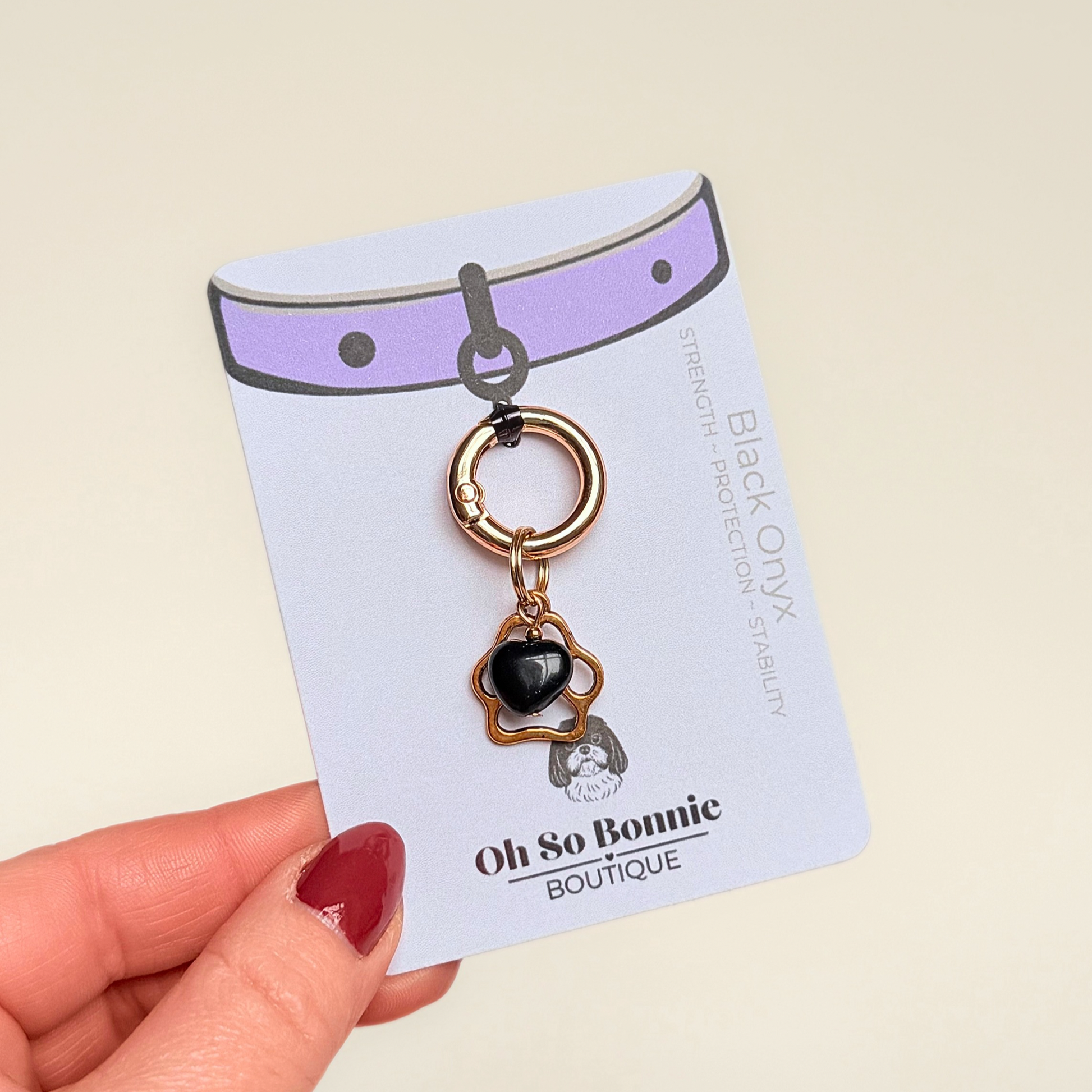 Crystal for dogs pet collar charm featuring a 10mm black onyx heart shaped bead and a brass gold coloured paw print tag. A stone for protection, strength and stability. Pictured on the display card