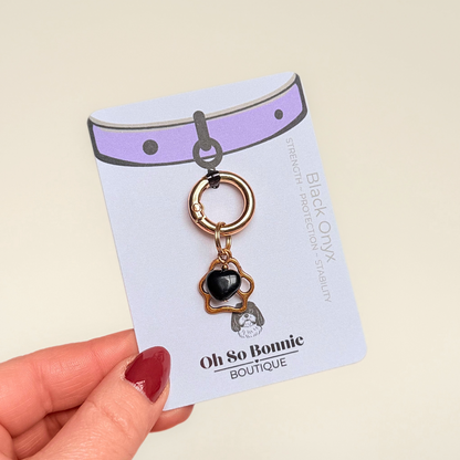 Crystal for dogs pet collar charm featuring a 10mm black onyx heart shaped bead and a brass gold coloured paw print tag. A stone for protection, strength and stability. Pictured on the display card